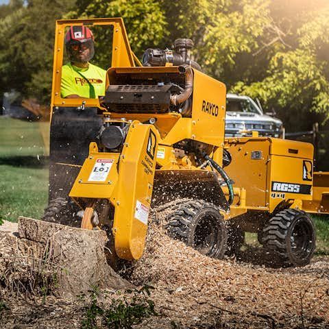 A man is using a stump grinder to remove a tree stump.