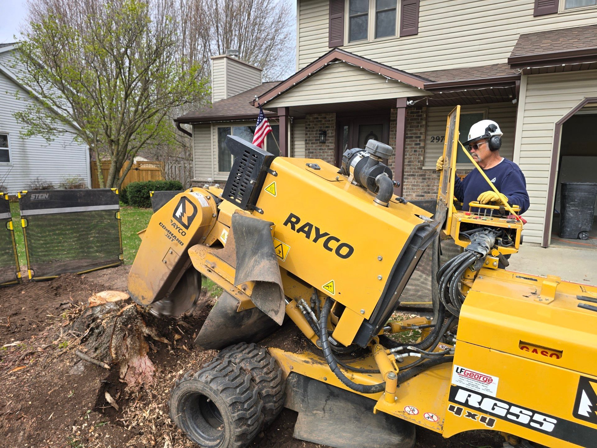 A man is operating a stump grinder in front of a house.