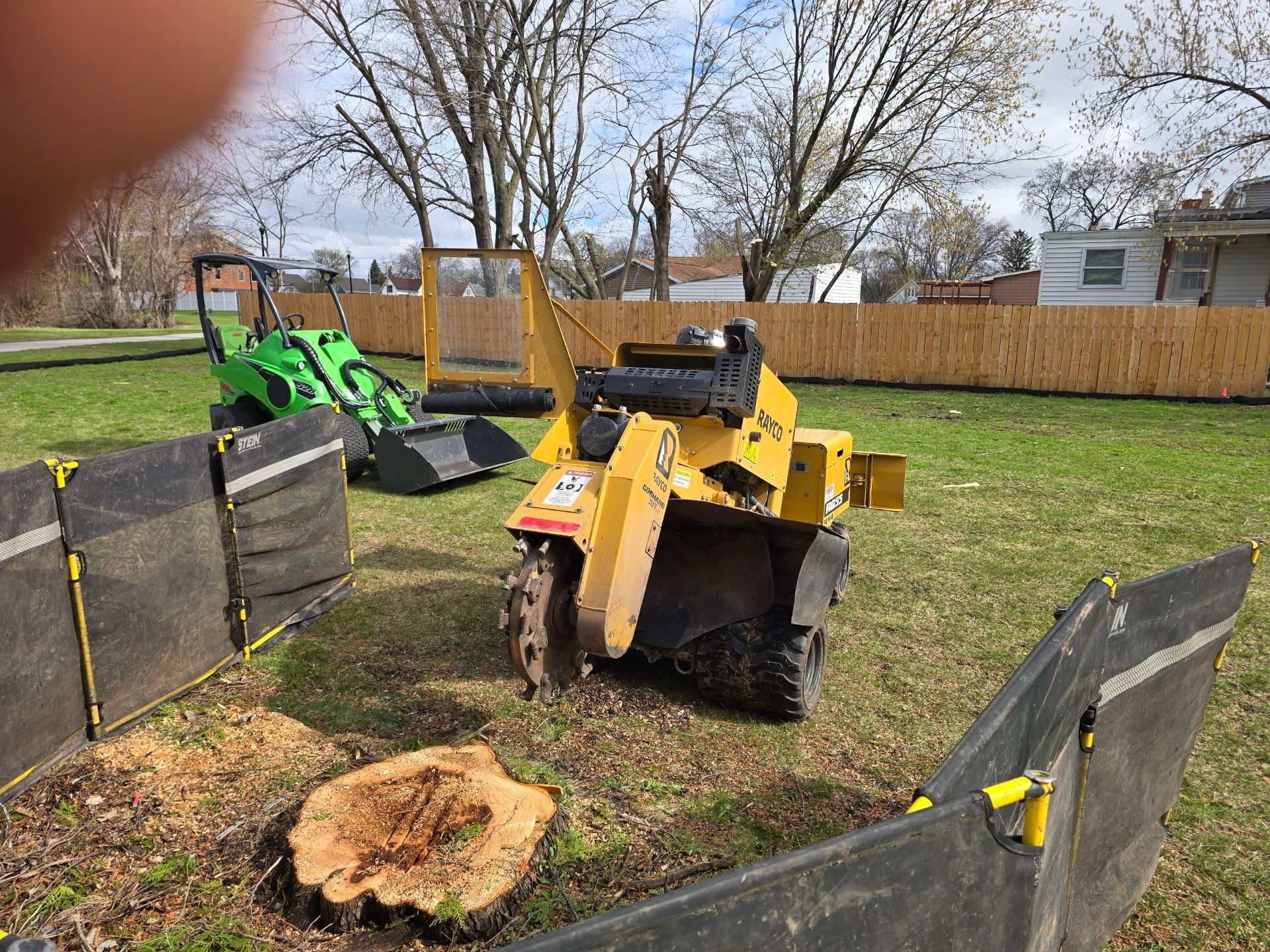 A stump grinder is sitting next to a tree stump in a yard.