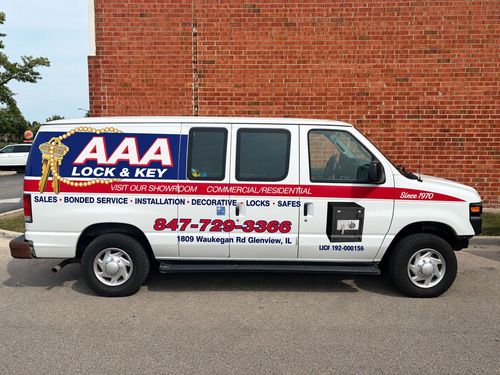 White AAA Lock & Key service van parked beside a brick wall, with red and blue lettering.
