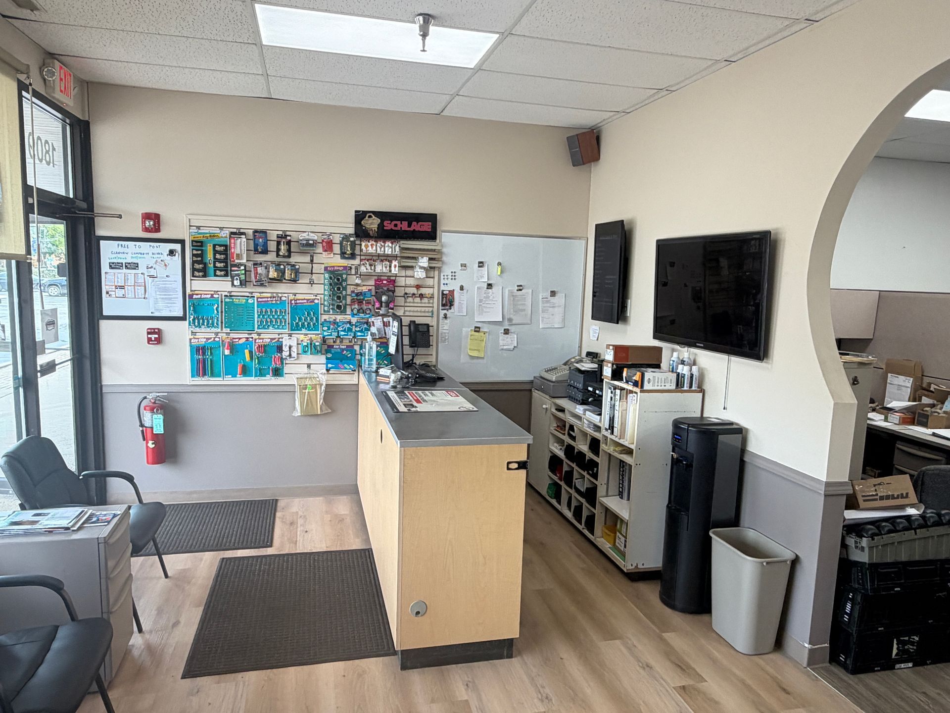 Reception area with a desk, wall display, TV, chairs, and office equipment.