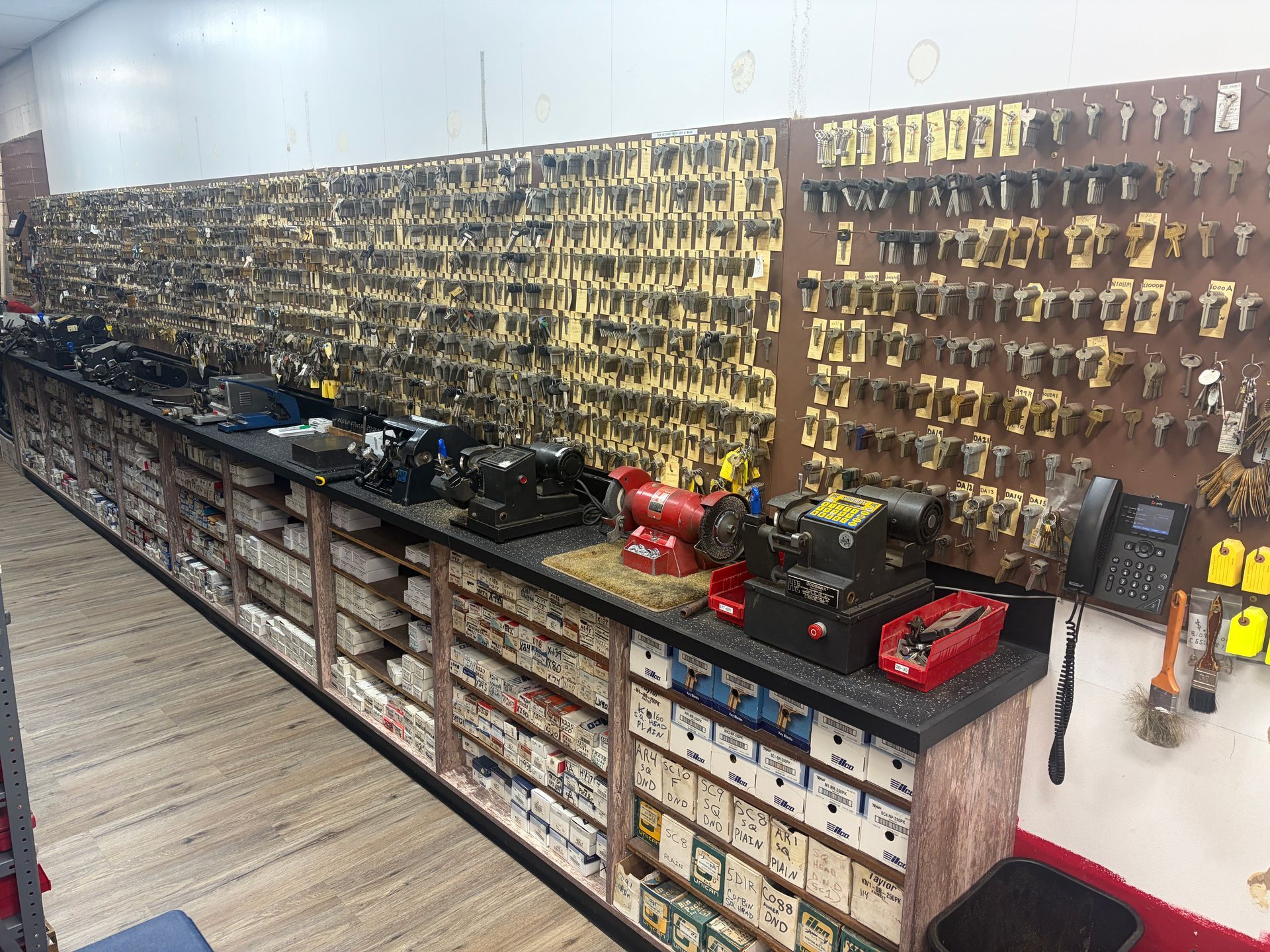 Wall of key blanks and a long locksmith workbench with tools and key-cutting machines
