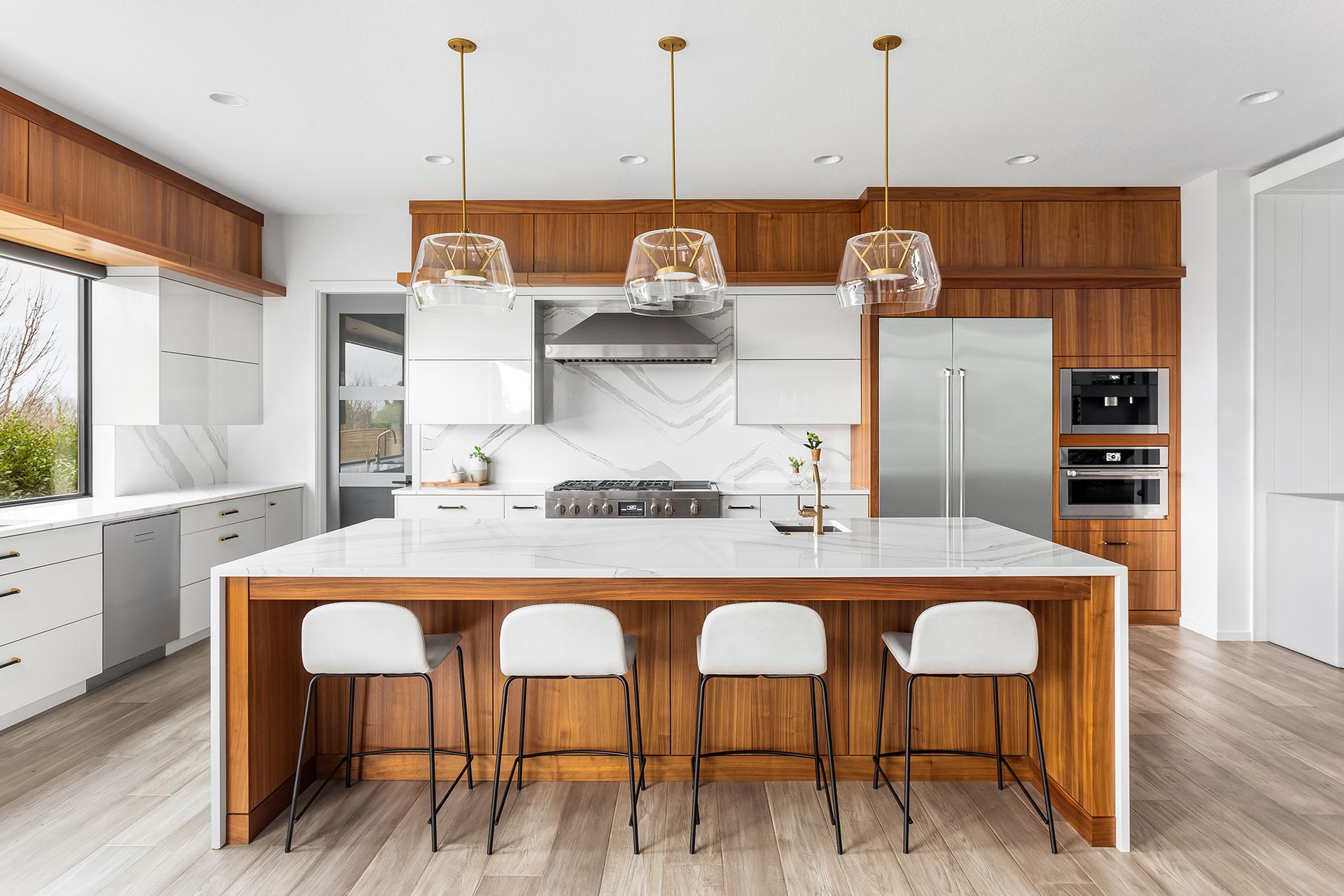 Modern kitchen with white cabinets, wood accents, a large island, and pendant lights