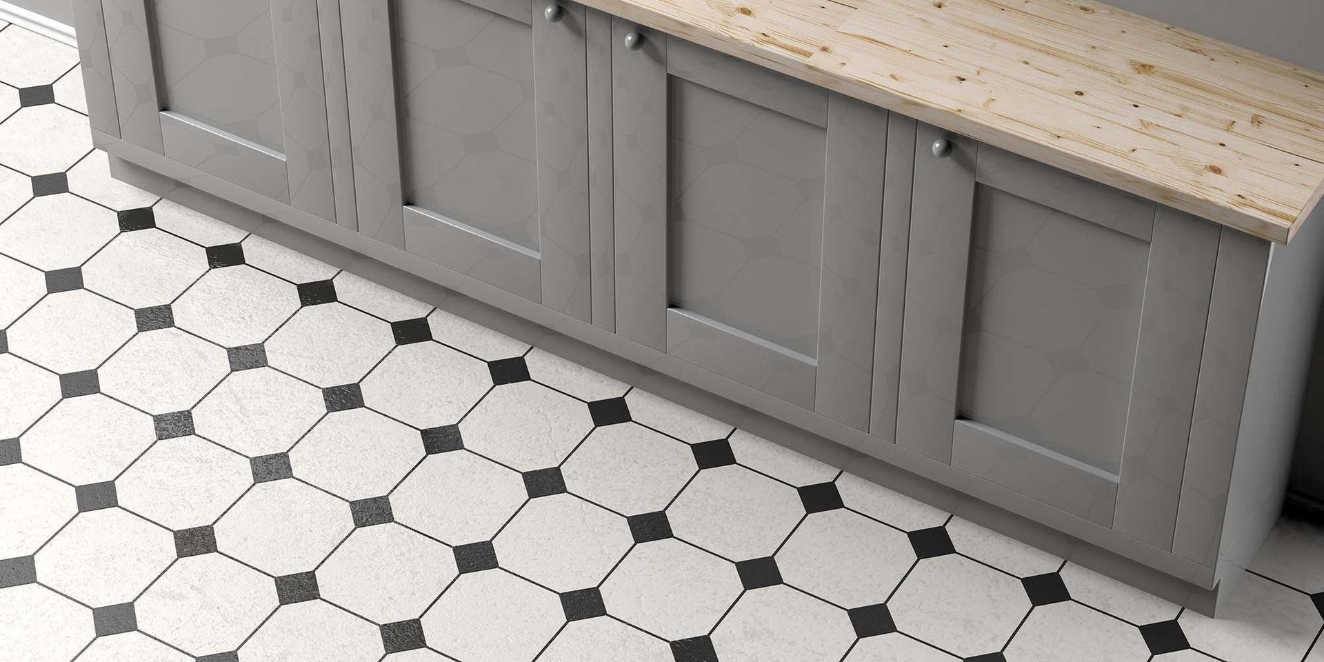 White hex tile floor with black accents beside gray kitchen cabinets and a light wood countertop