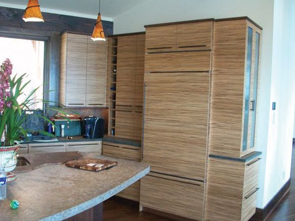Modern kitchen with wood cabinets, a large island, pendant lights, and a vase of flowers ליד window