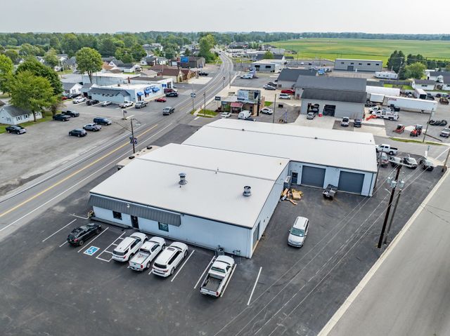 Aerial view of a commercial building and parking lot beside a road in a small town.
