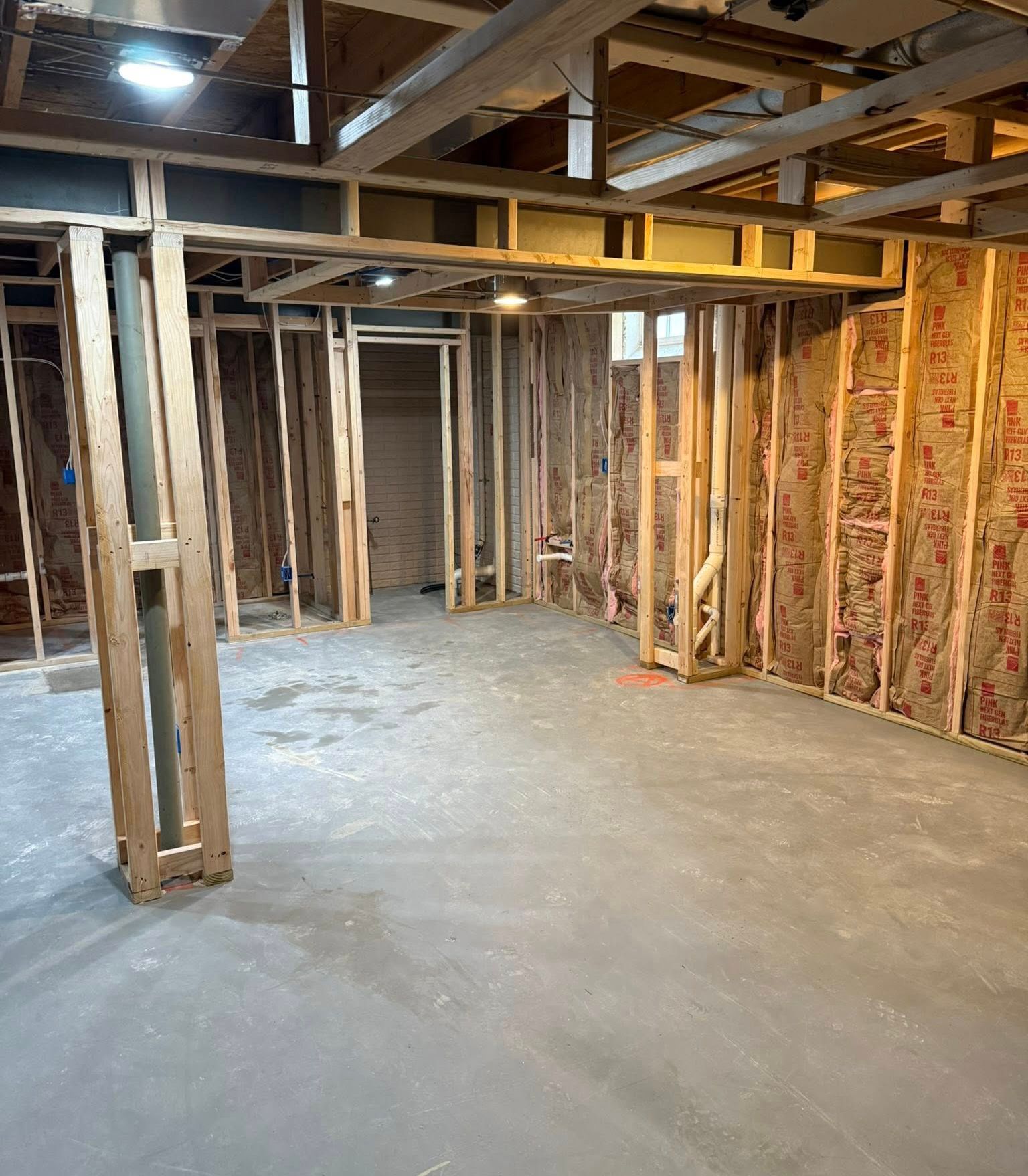 Unfinished basement with exposed framing, concrete floor, and insulated wall studs.