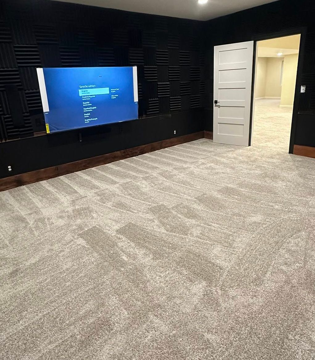 Carpeted room with dark walls, wall-mounted TV, and an open white door to a lit hallway