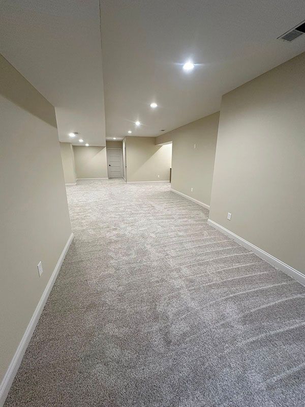 Empty carpeted basement with beige walls and recessed ceiling lights