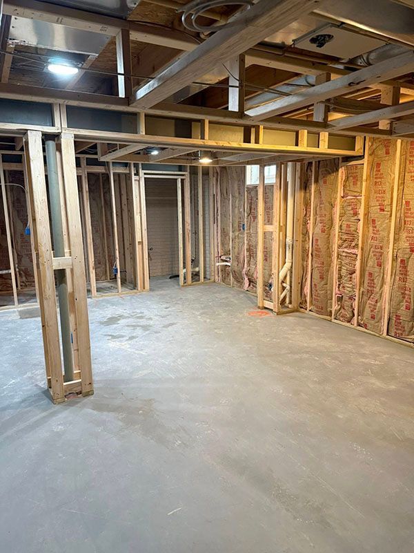 Unfinished basement with exposed wood framing, concrete floor, and insulation along the walls