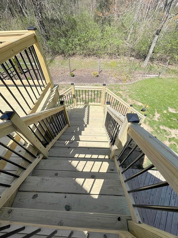 Wooden outdoor staircase descending to a backyard, with railings