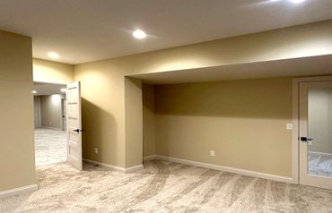 Empty room with gray walls, wood floors, white doors, and a small sink and counter area