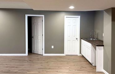 Empty beige basement room with carpet, recessed lights, and doorways