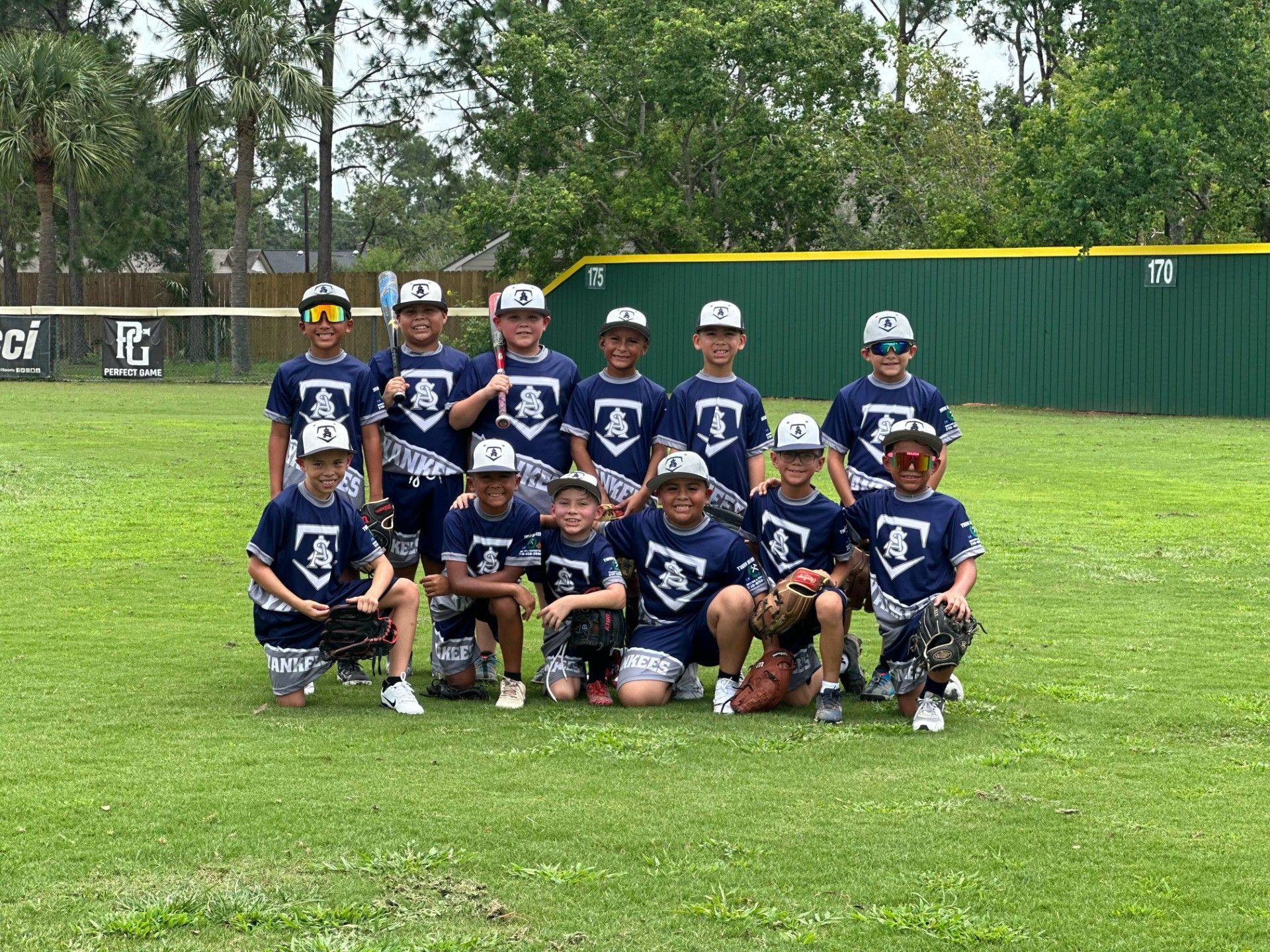 A group of young boys are posing for a picture on a baseball field.
