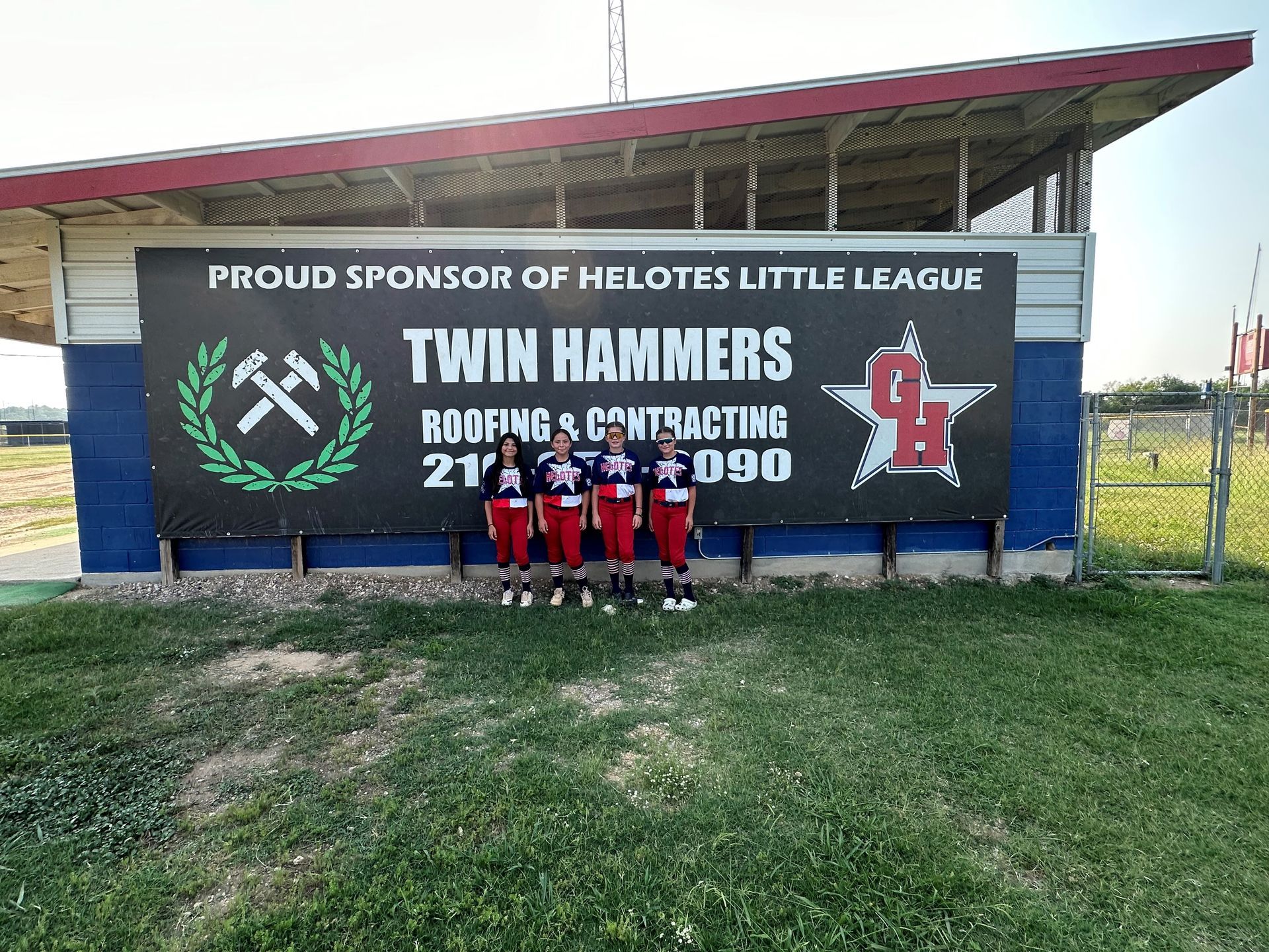 A group of people standing in front of a sign that says twin hammers roofing and contracting.