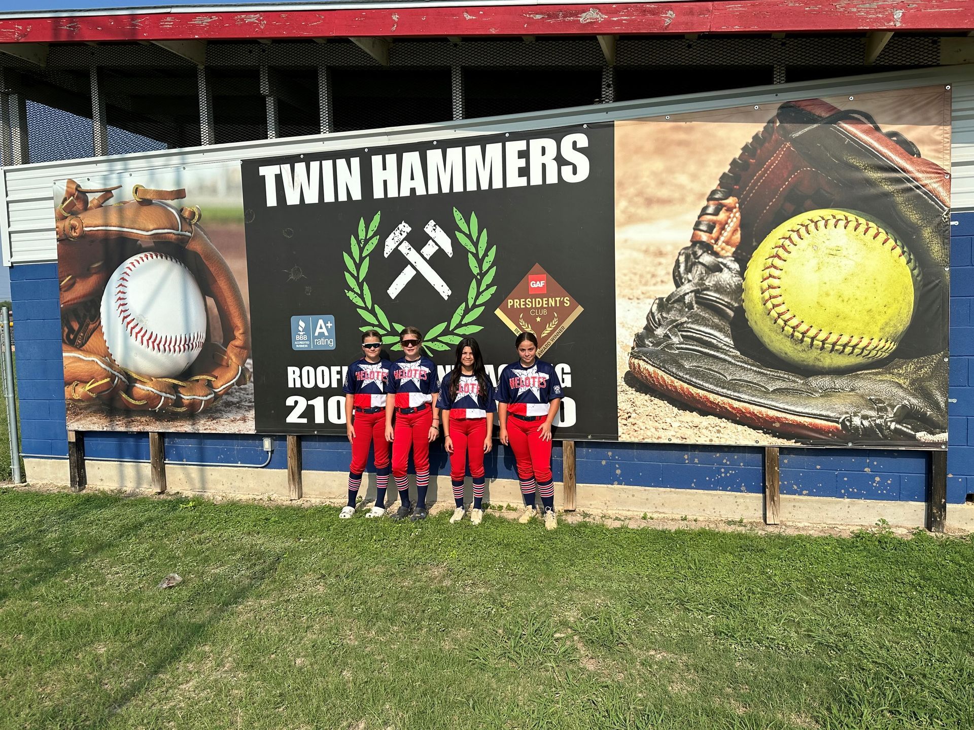 A group of baseball players standing in front of a billboard that says twin hammers