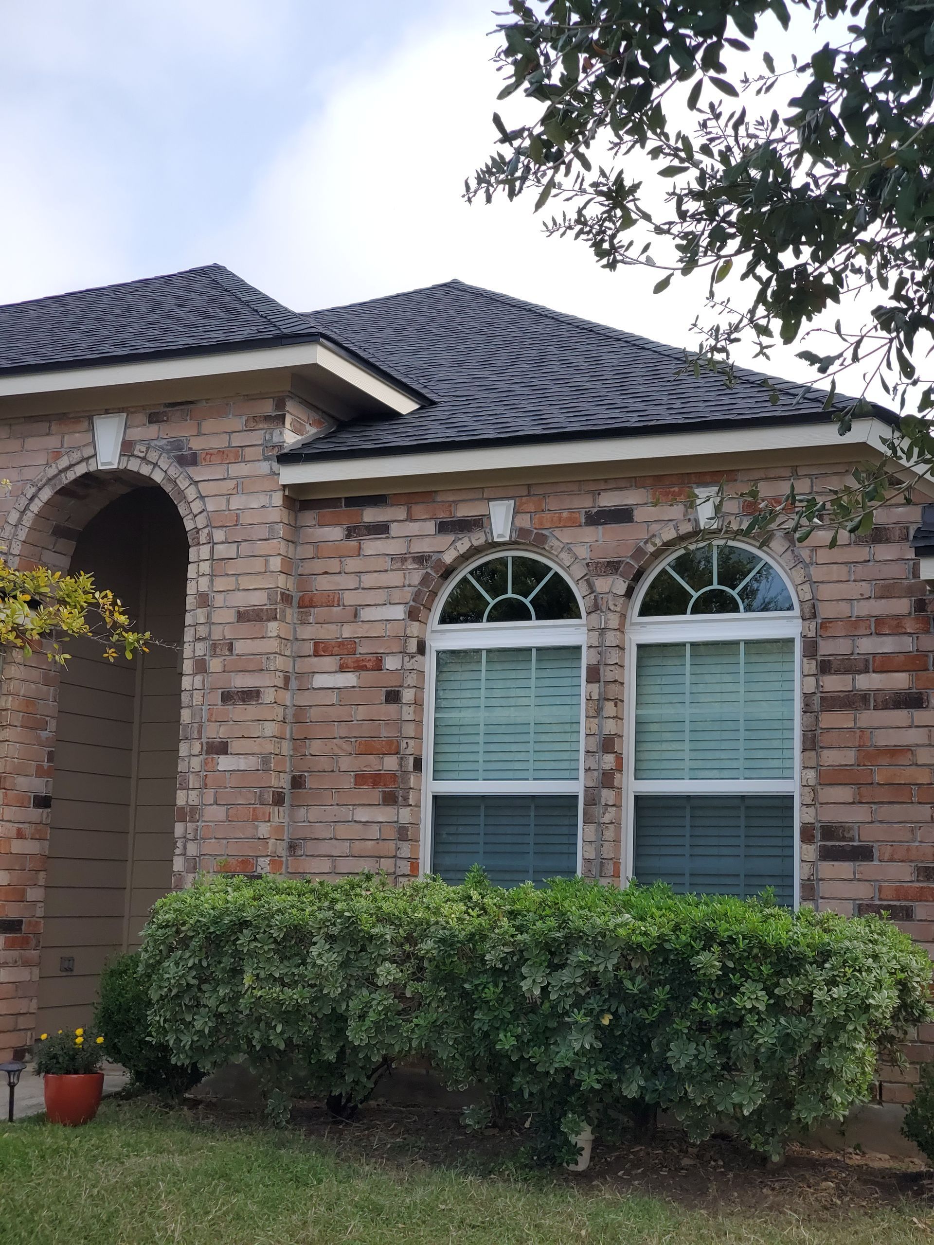 A brick house with arched windows and a black roof