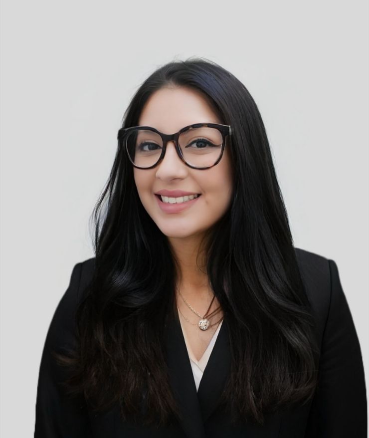 A woman wearing glasses and a black jacket smiles for the camera