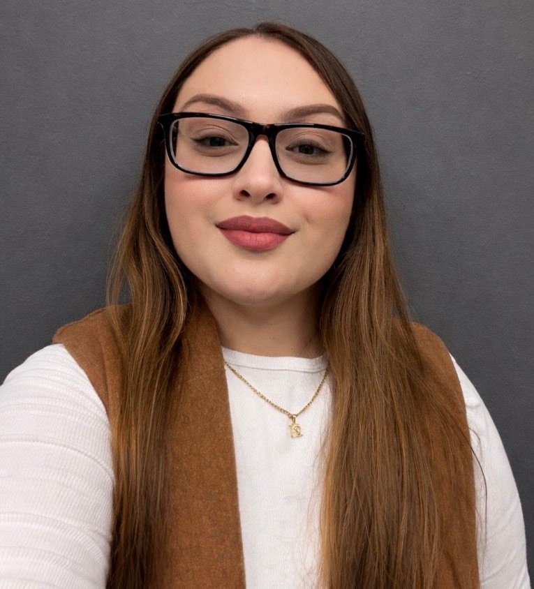 The woman is wearing glasses and a green sweater.