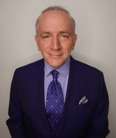 A man in a suit and tie is smiling for the camera.