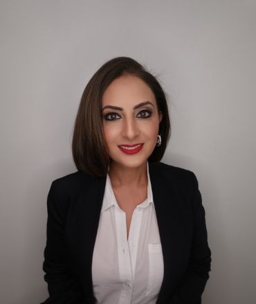 A woman wearing a black jacket and a white shirt is smiling for the camera.