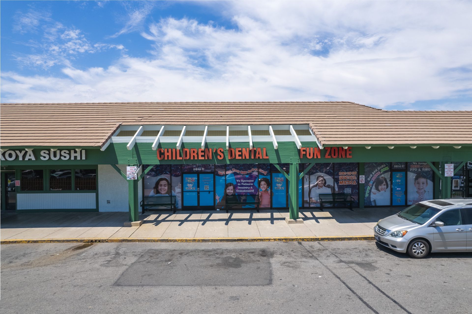 A white van is parked in front of a children 's dental office.