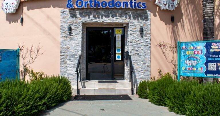 A sign for a children 's dental office is outside of a building.