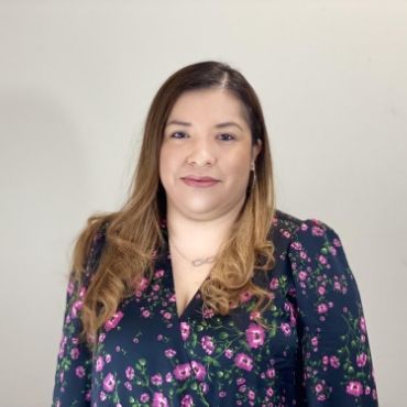 A woman is wearing a floral shirt and a necklace.