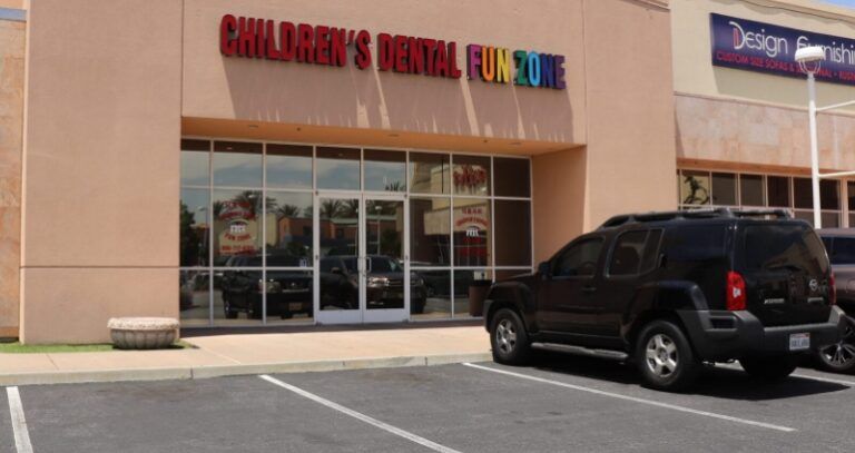 A black suv is parked in front of a children 's dental clinic