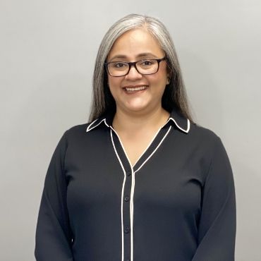 A woman wearing glasses and a black shirt is smiling for the camera.