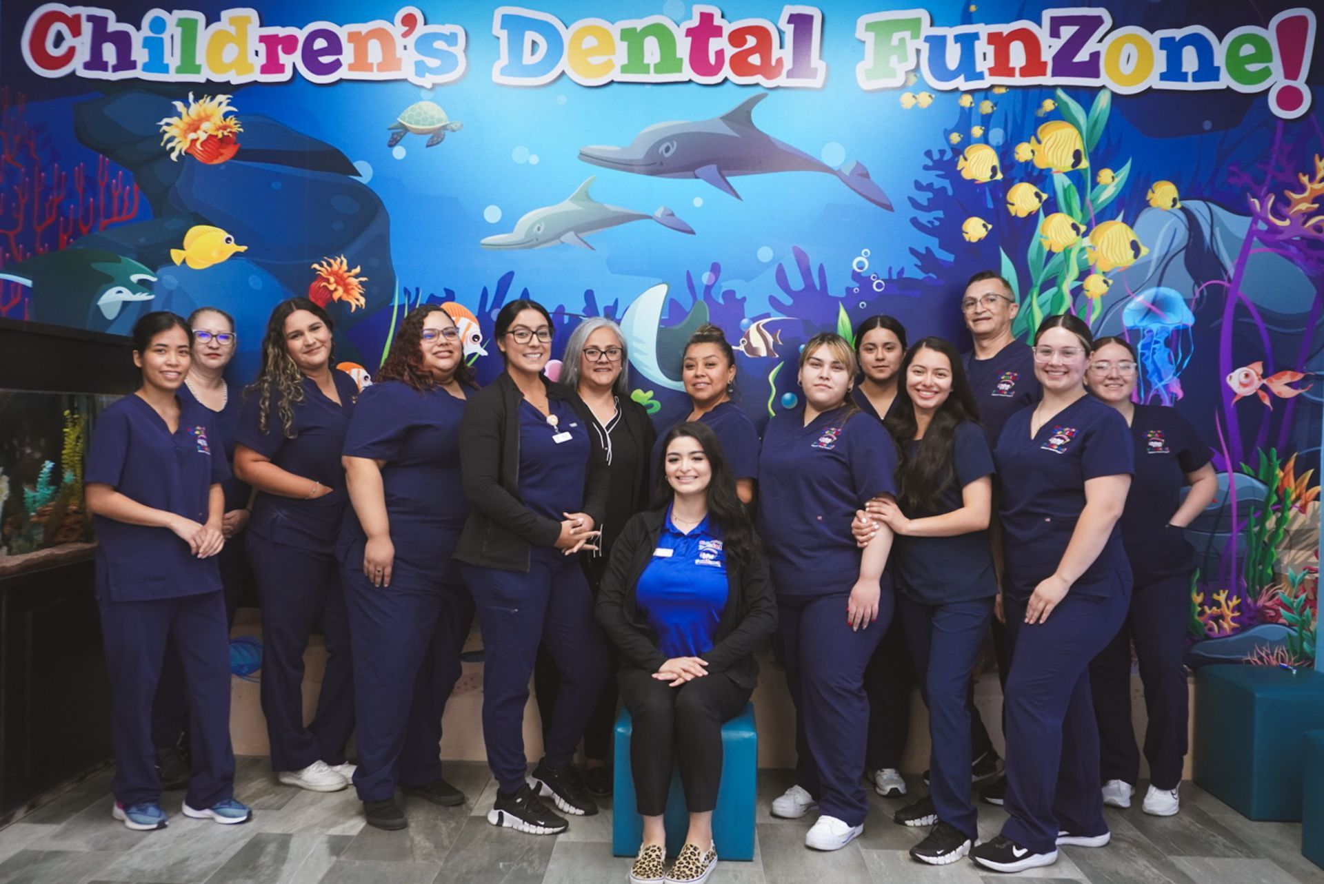 A group of people posing for a picture in front of a sign that says children 's dental funzone