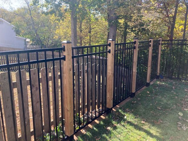 Wooden backyard fence with a central gate and metal hinges on a dirt and grass ground