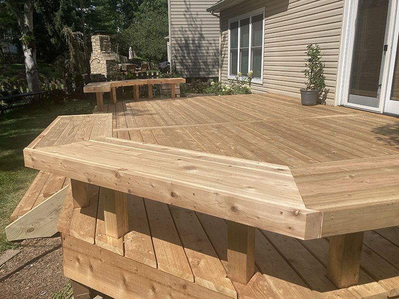 Wooden backyard deck with benches beside a house, viewed from the corner.