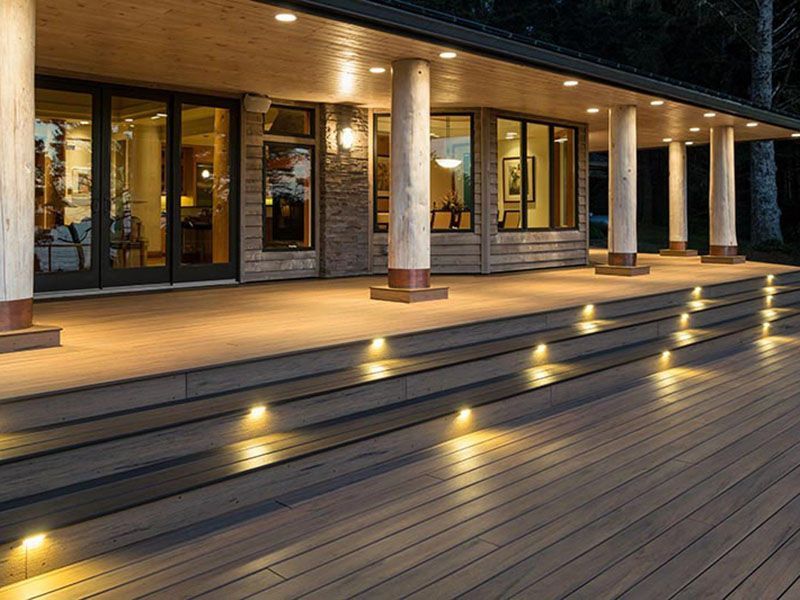 Modern building entrance at dusk with lit steps and a wooden deck under warm lights