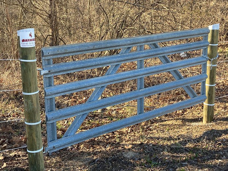 Blue metal gate on wooden posts in a dry, grassy field
