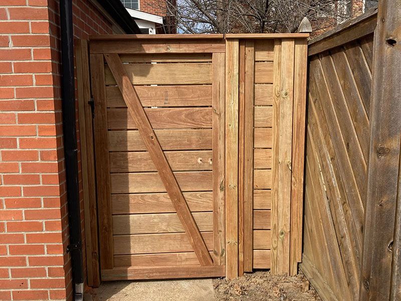 Wooden garden gate with diagonal brace beside a brick wall and fence panels