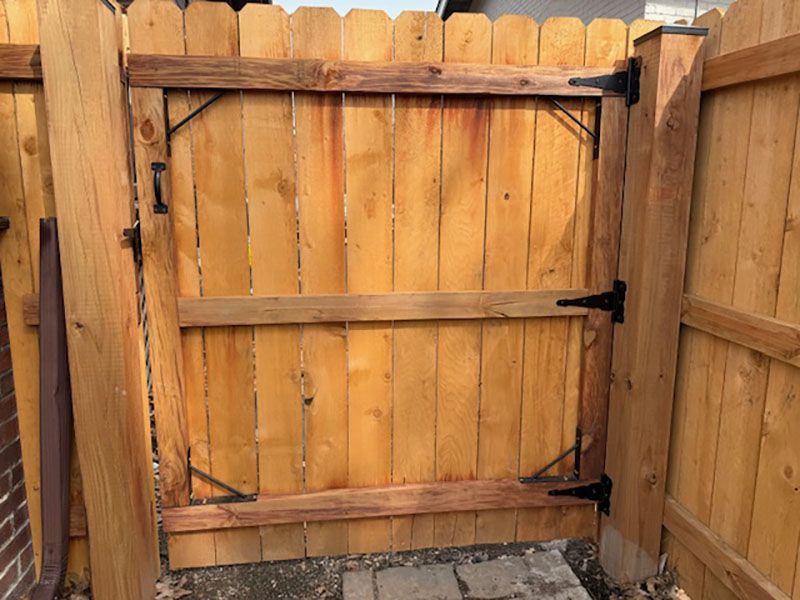 Wooden fence gate frame with horizontal braces between two privacy fence panels.