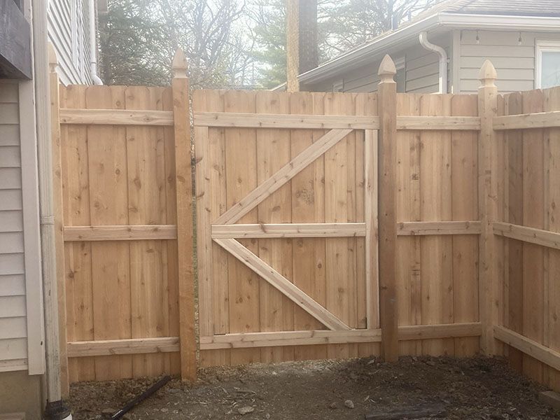 Wooden backyard fence with a diagonal-braced gate and privacy panels, viewed from inside the yard.
