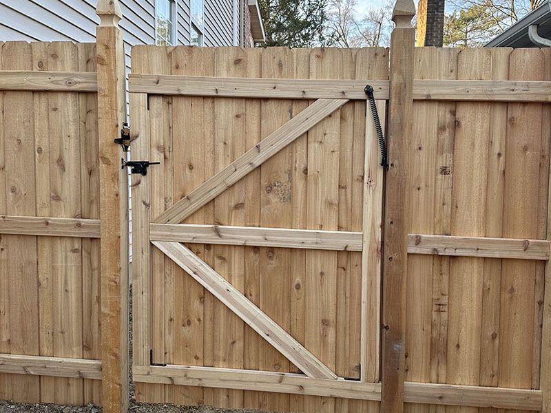 Wooden backyard gate with diagonal braces in a fenced yard