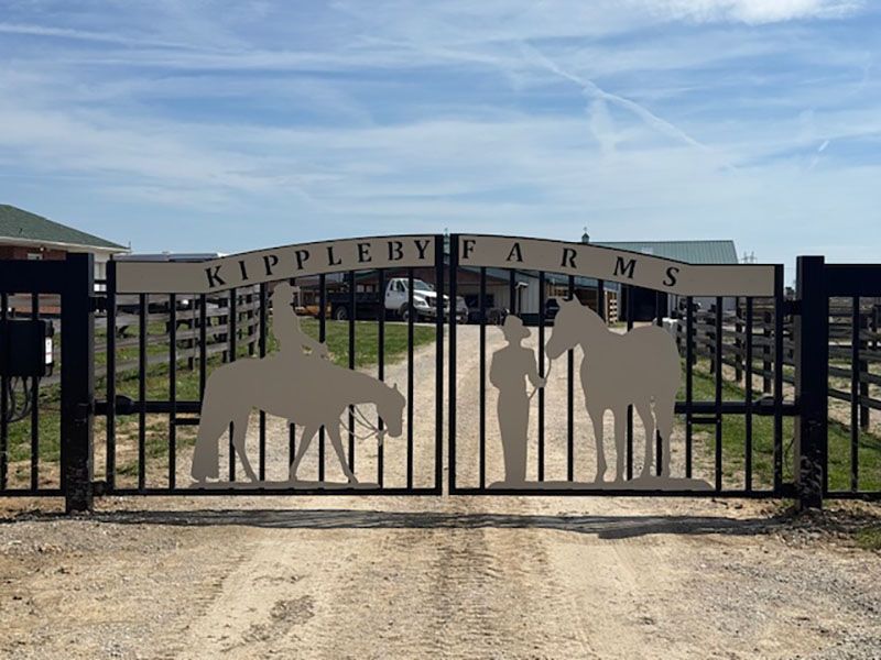 Entrance gate to Kippleby Farms with a pig and farmer silhouettes under a blue sky