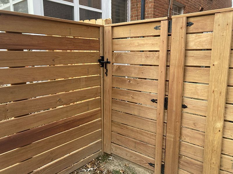 Wooden privacy fence corner with a black latch on the gate, viewed outdoors.