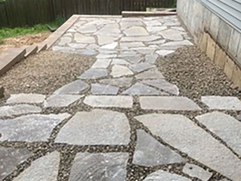 Stone-paved garden path bordered by gravel and wooden fences