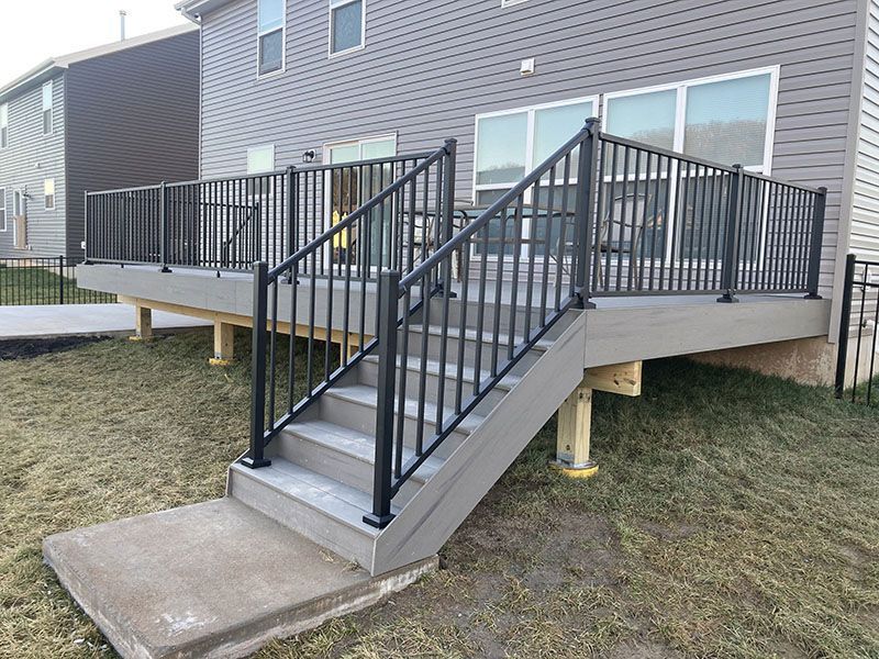 Accessible apartment deck with black railings and a concrete ramp leading to it