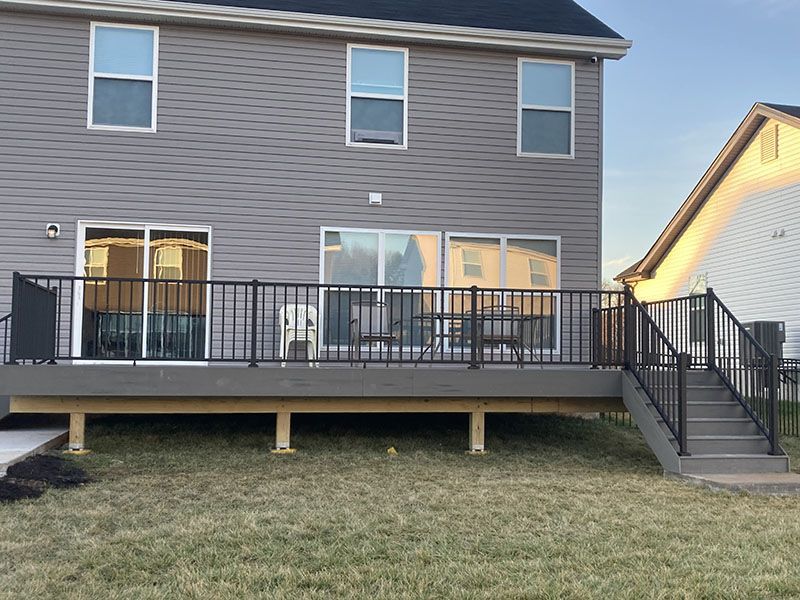 Backyard deck on a two-story house with black railing and stairs to the lawn