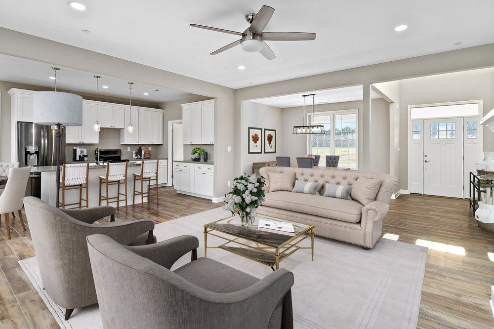 A living room with a couch, chairs, a coffee table, and a ceiling fan.