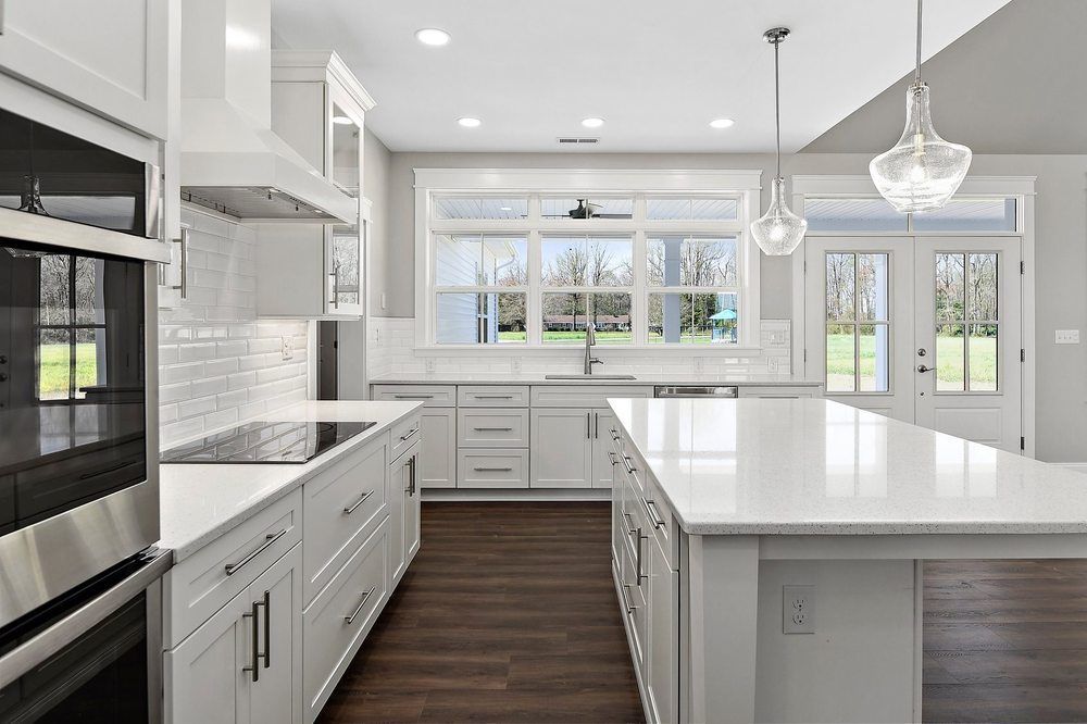 A kitchen with white cabinets, stainless steel appliances, and a large island.