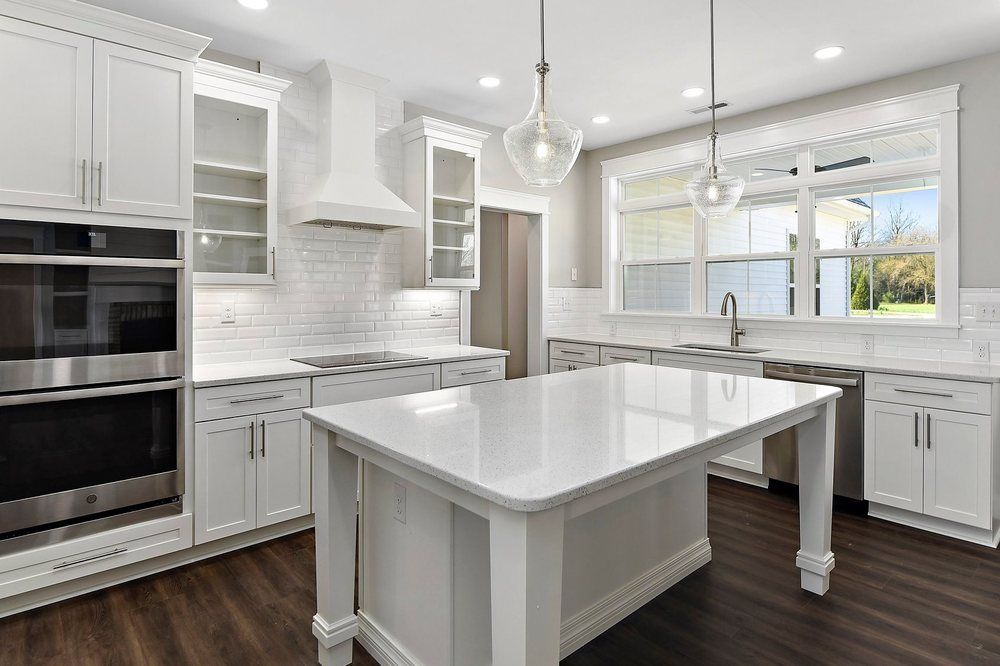A kitchen with white cabinets, stainless steel appliances, and a large island.