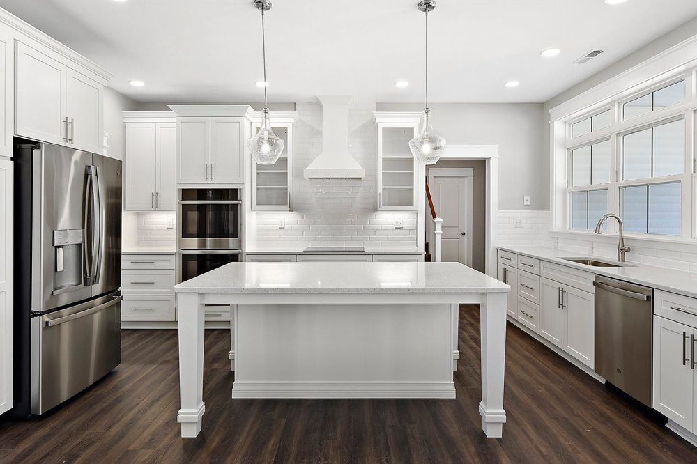 A kitchen with white cabinets, stainless steel appliances, and a large island.