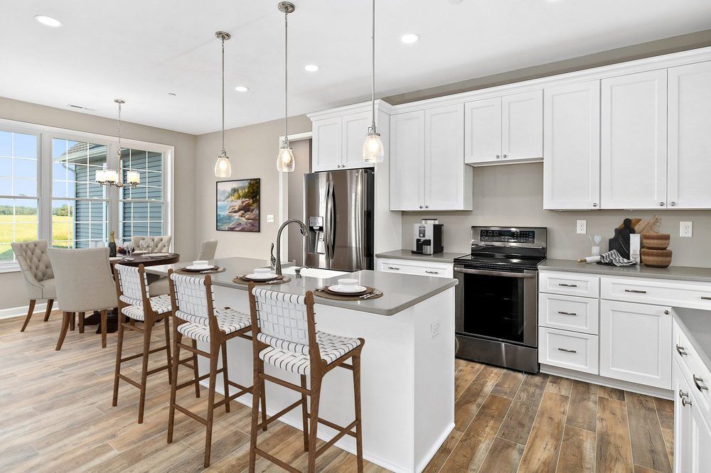 A kitchen in a model home with white cabinets and stainless steel appliances.