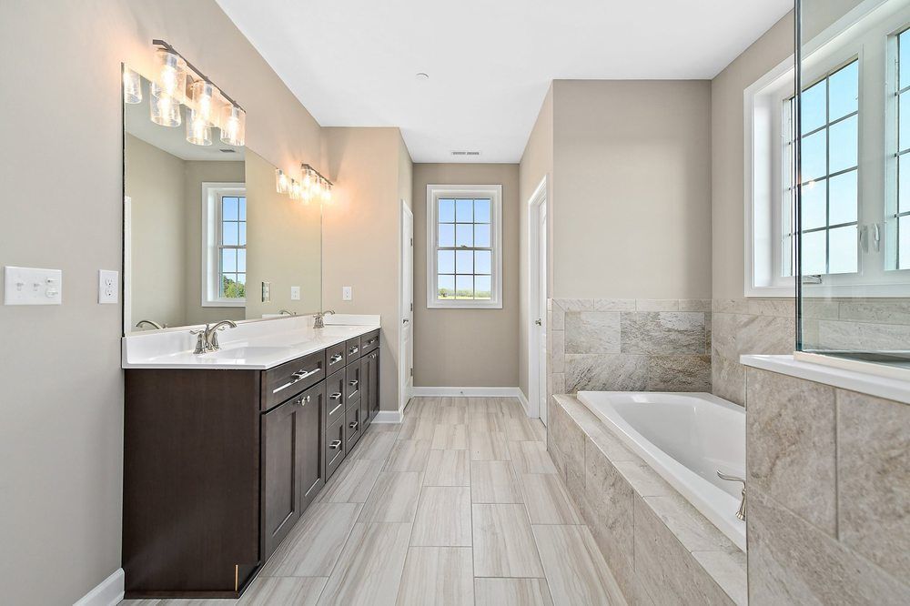 A bathroom with two sinks, a tub, and a mirror.